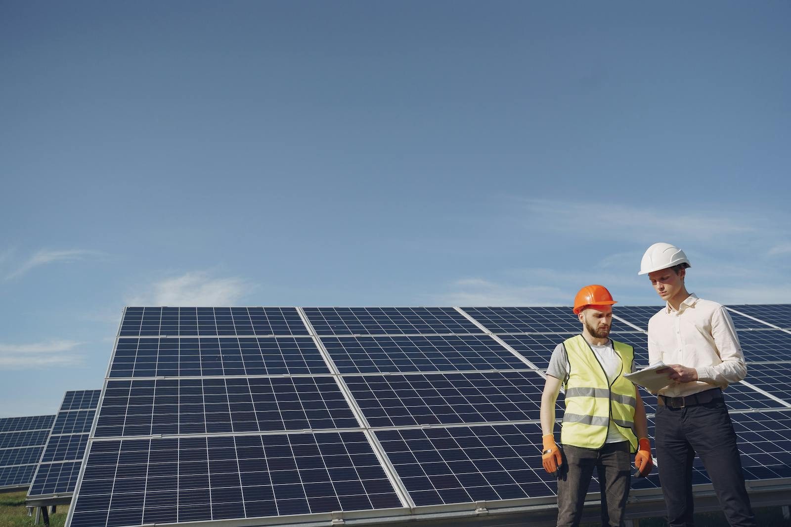An advisor and a site engineer reviewing project plans beside a solar array